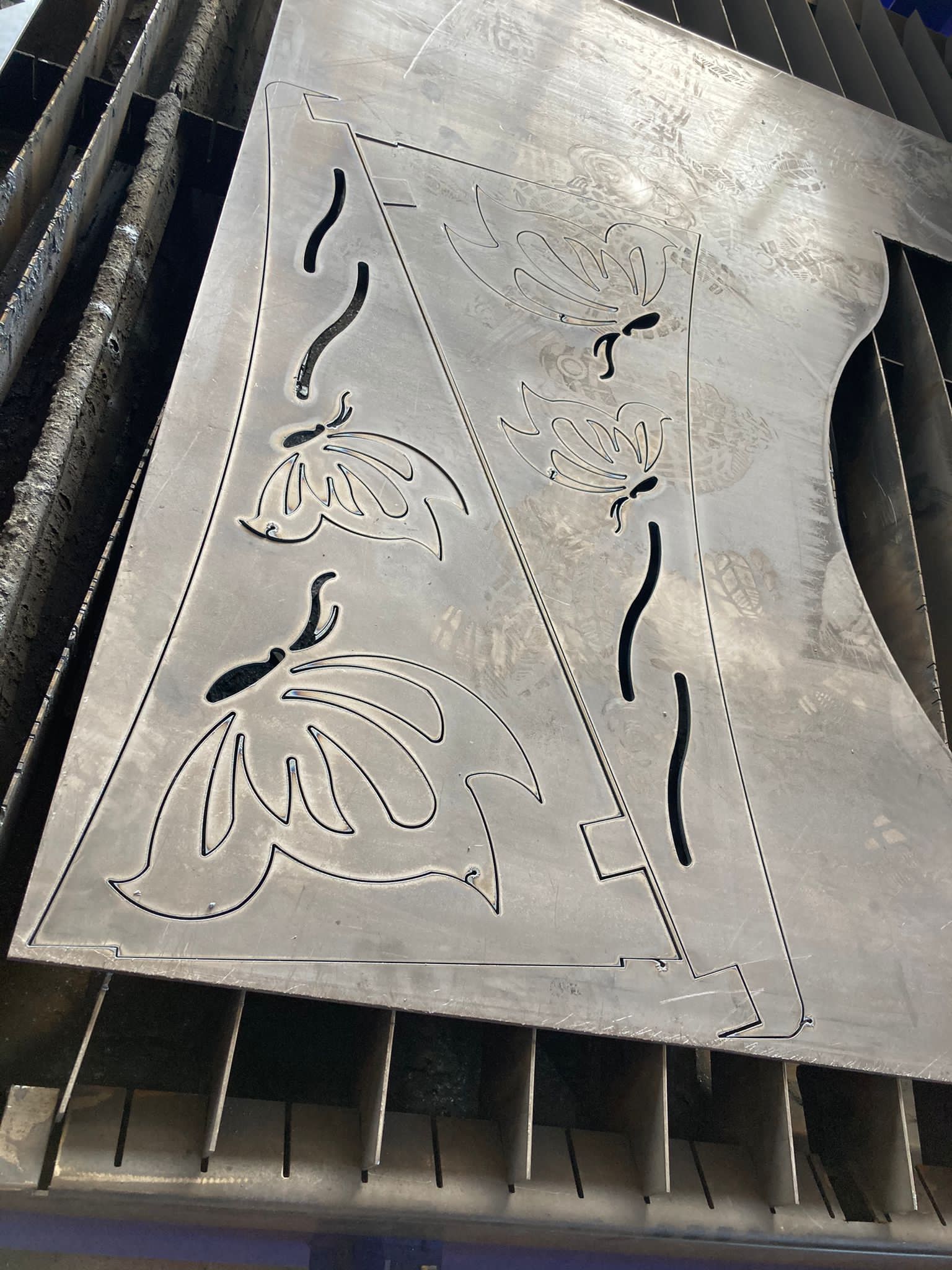 Lamiera con motivo floreale tagliato al laser e ritaglio triangolare. Appoggiata su una superficie scanalata.