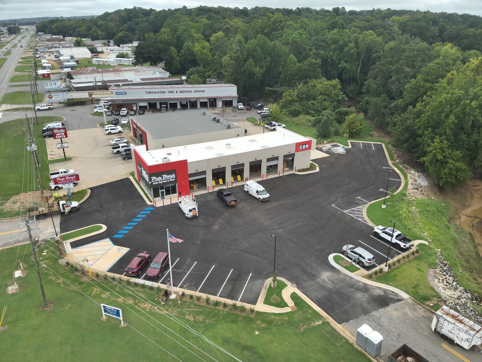Aerial view of a car repair shop with a red and gray facade, vehicles, and a parking lot.