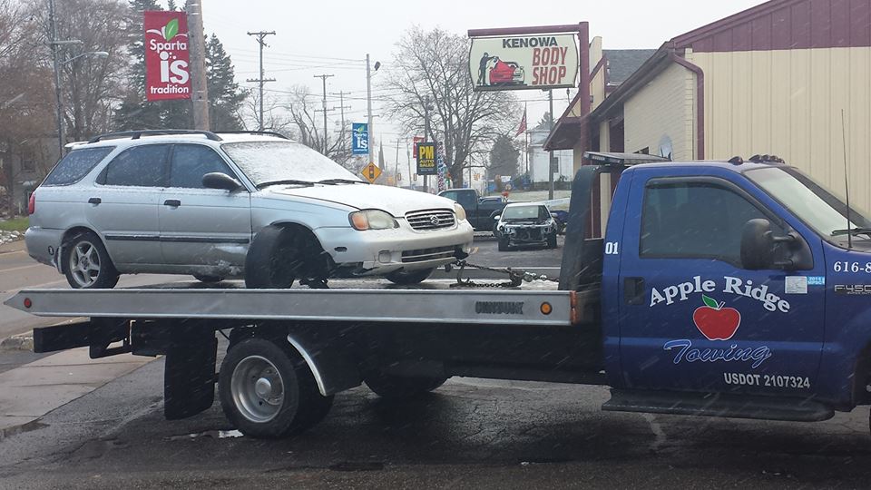 a blue apple ridge towing truck is towing a car