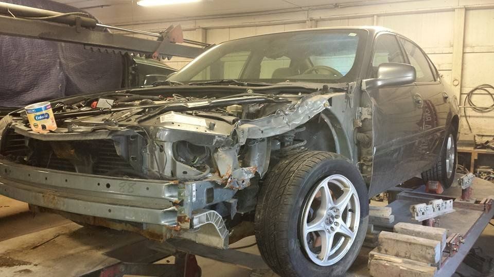 a car is being worked on in a garage with a container of kleenex on the hood