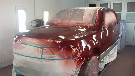 a red truck is being painted in a paint booth