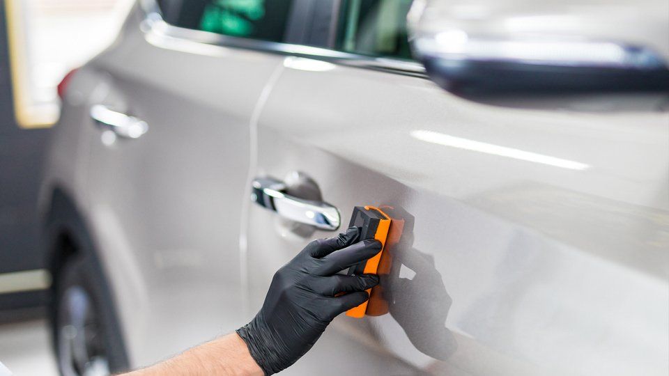 a person wearing black gloves is polishing a car door