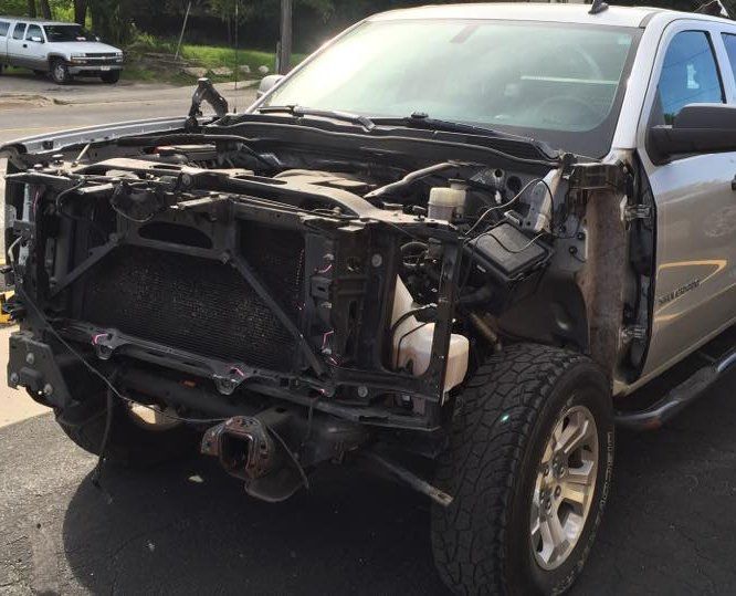 a silver truck with the front end removed is parked on the side of the road .