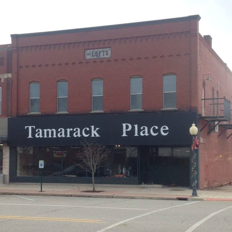 A brick building with a black sign that says tamarack place