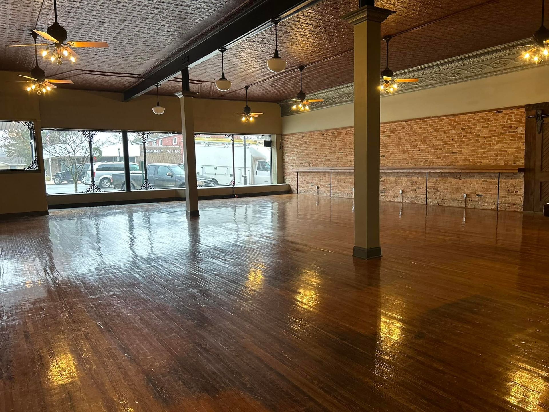 A large empty room with wooden floors and ceiling fans