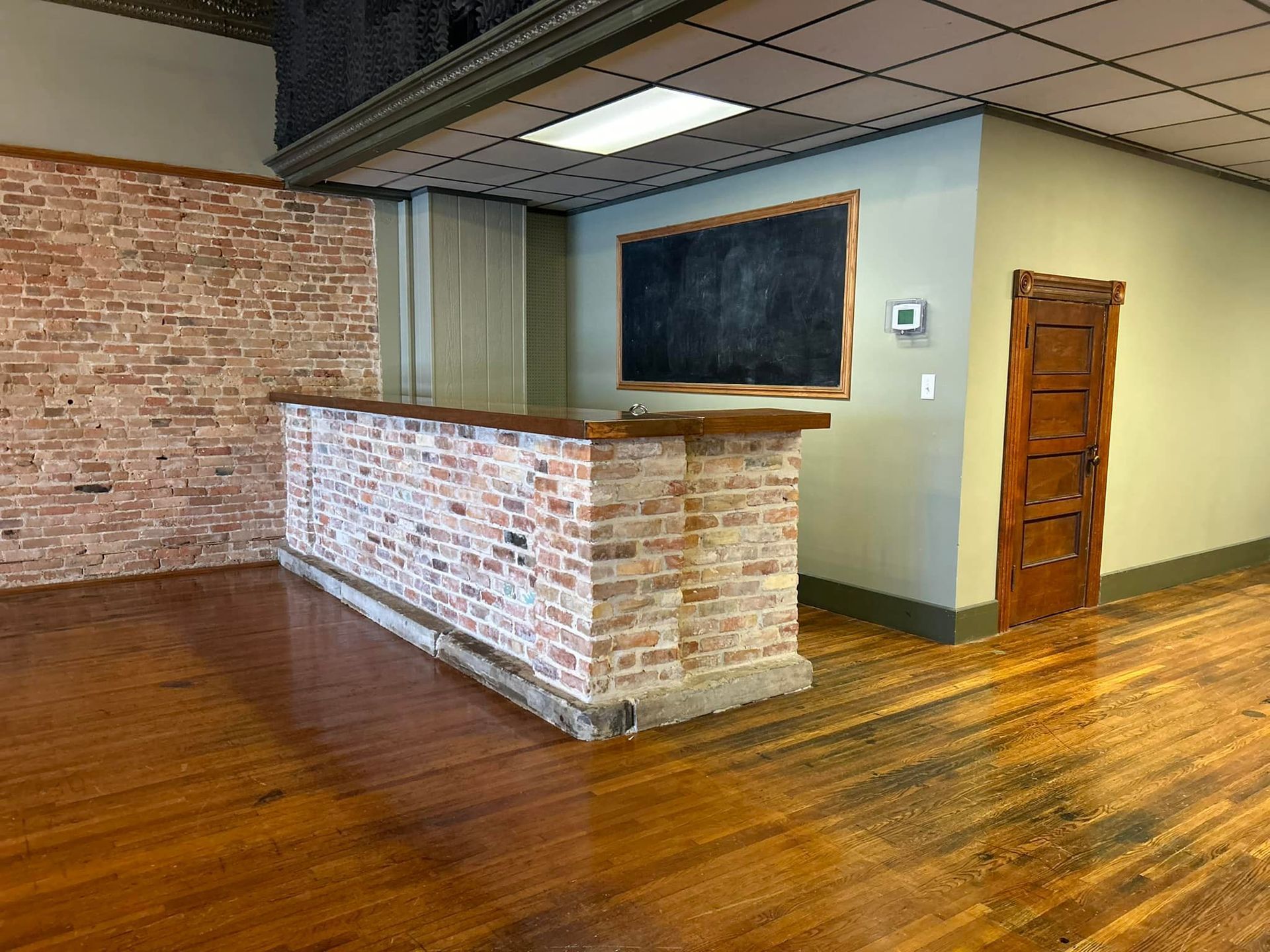 An empty room with a brick wall and a wooden floor.