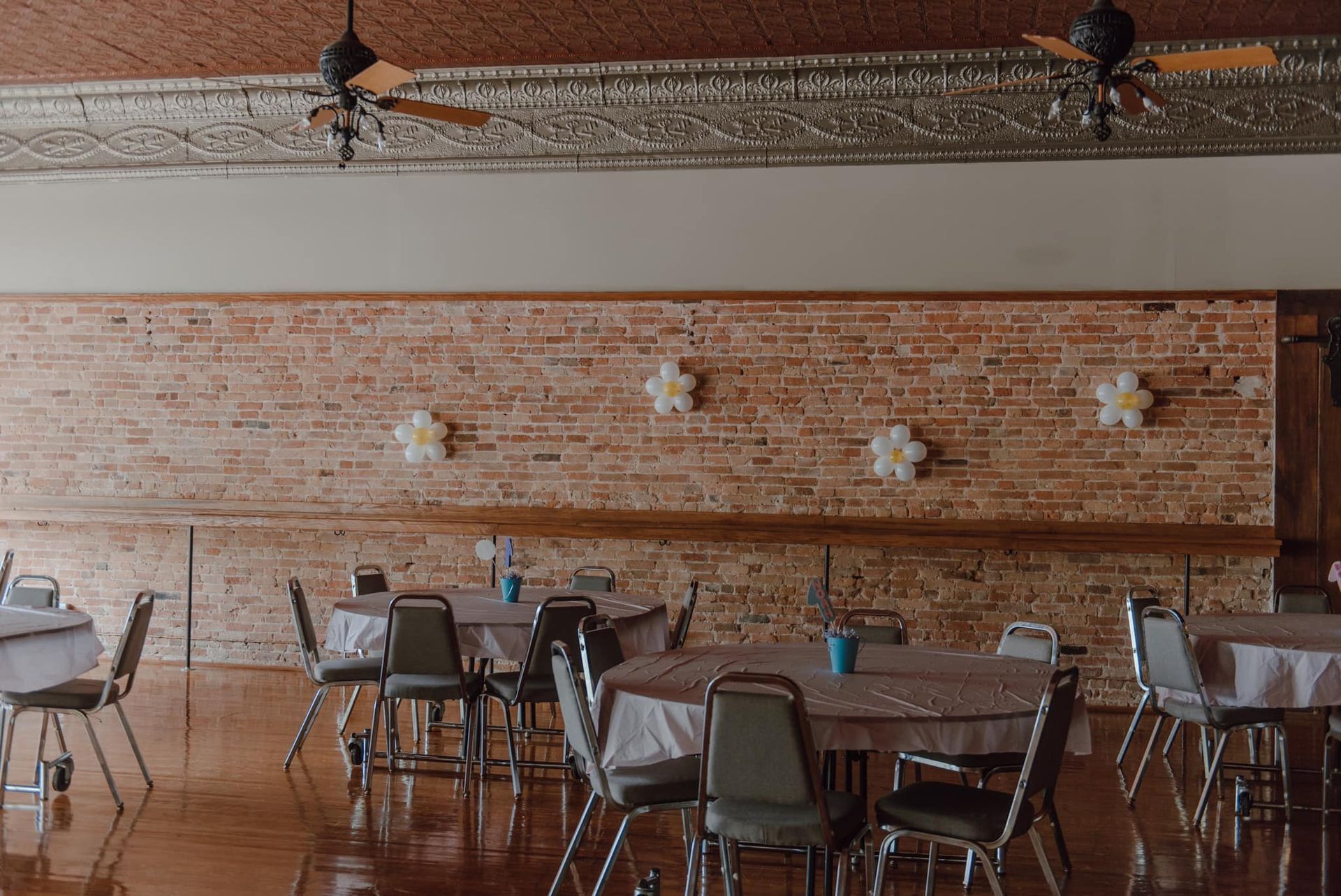 A large room with tables and chairs and balloons on the wall.