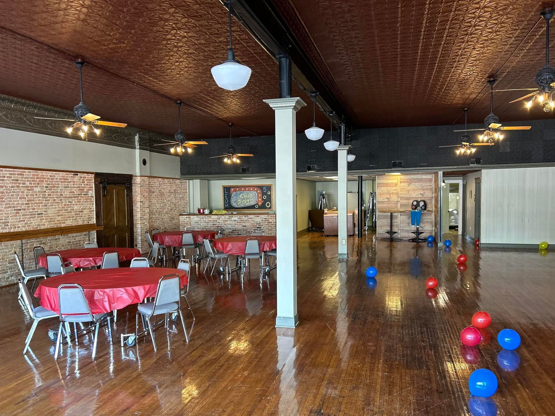 A large room with tables and chairs and balloons on the floor.