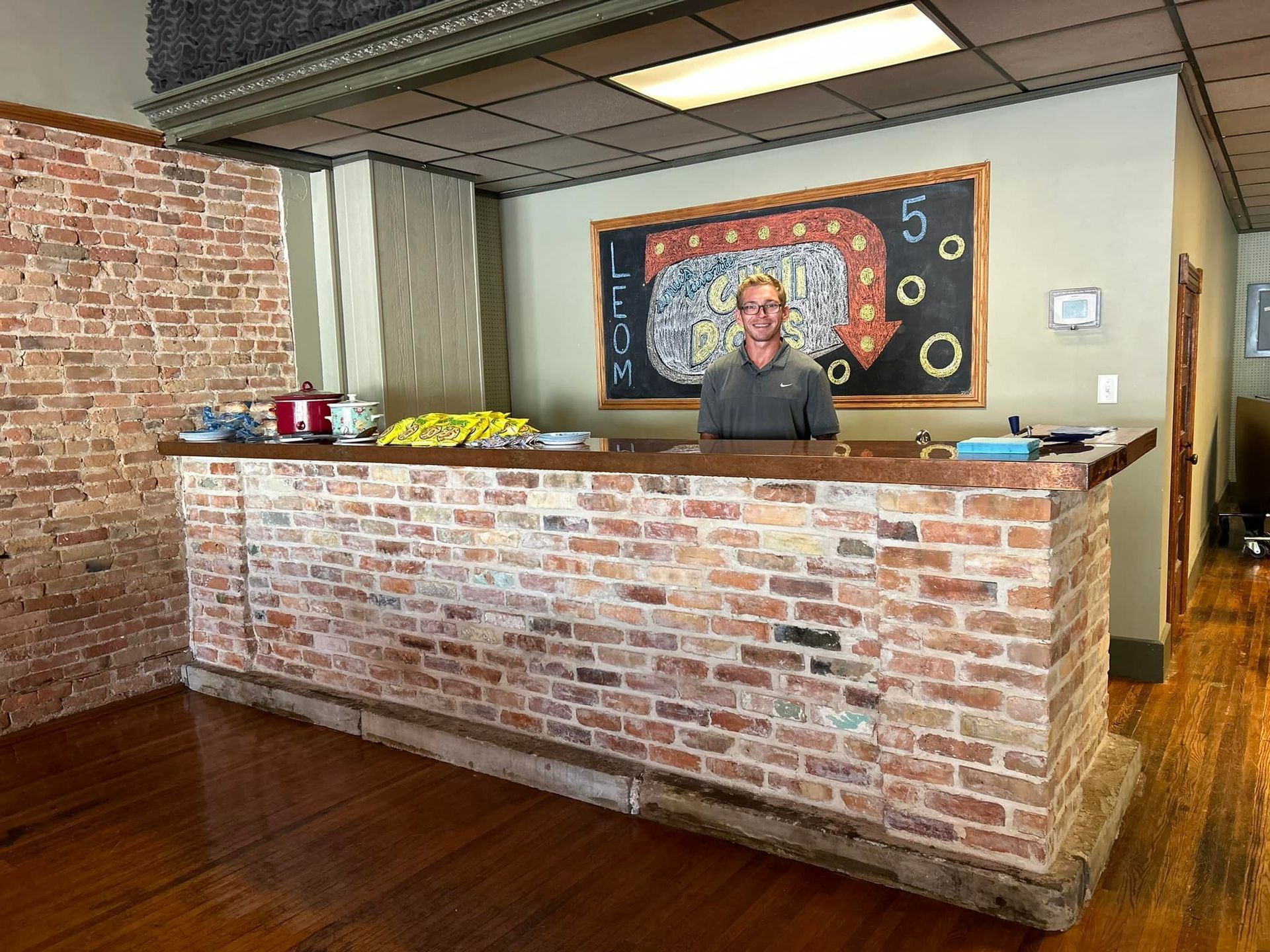 A man is standing behind a brick counter in a restaurant.