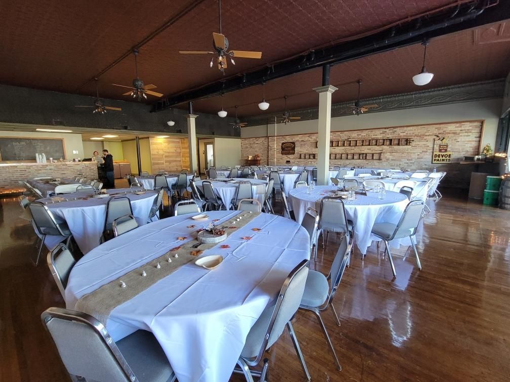 A large room with tables and chairs set up for a wedding reception.