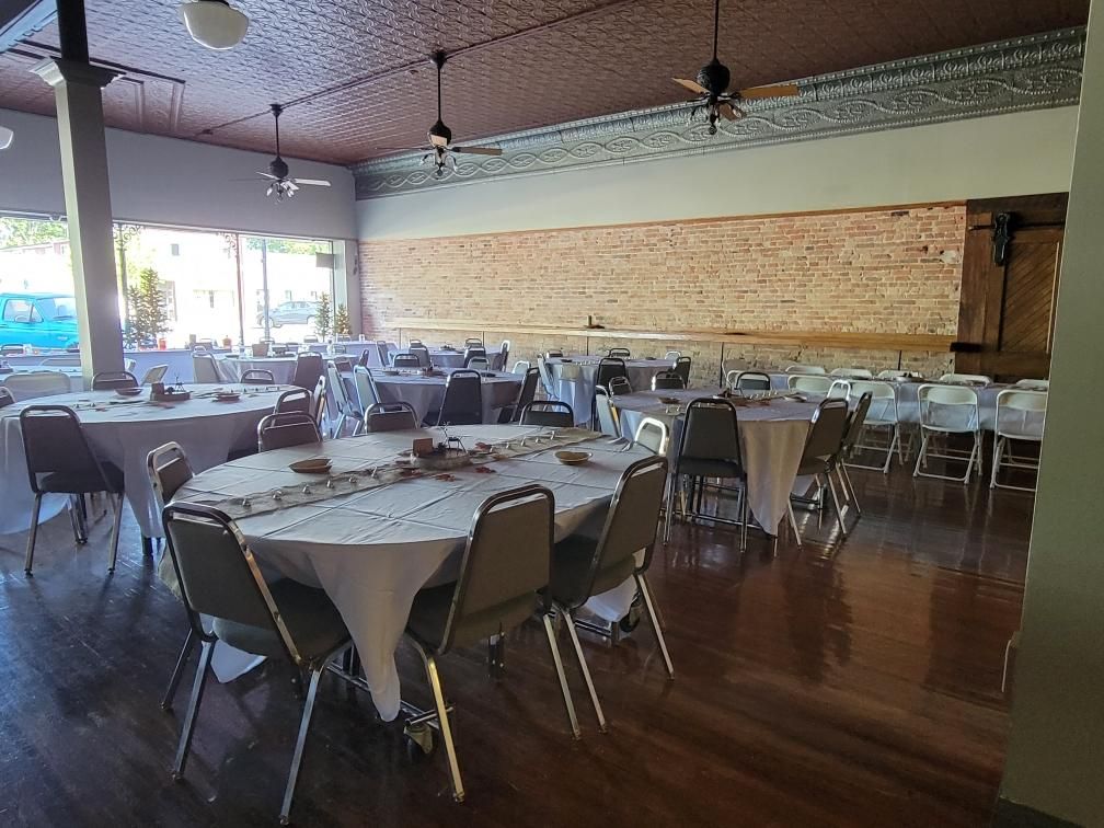 A large room with tables and chairs set up for a wedding reception.