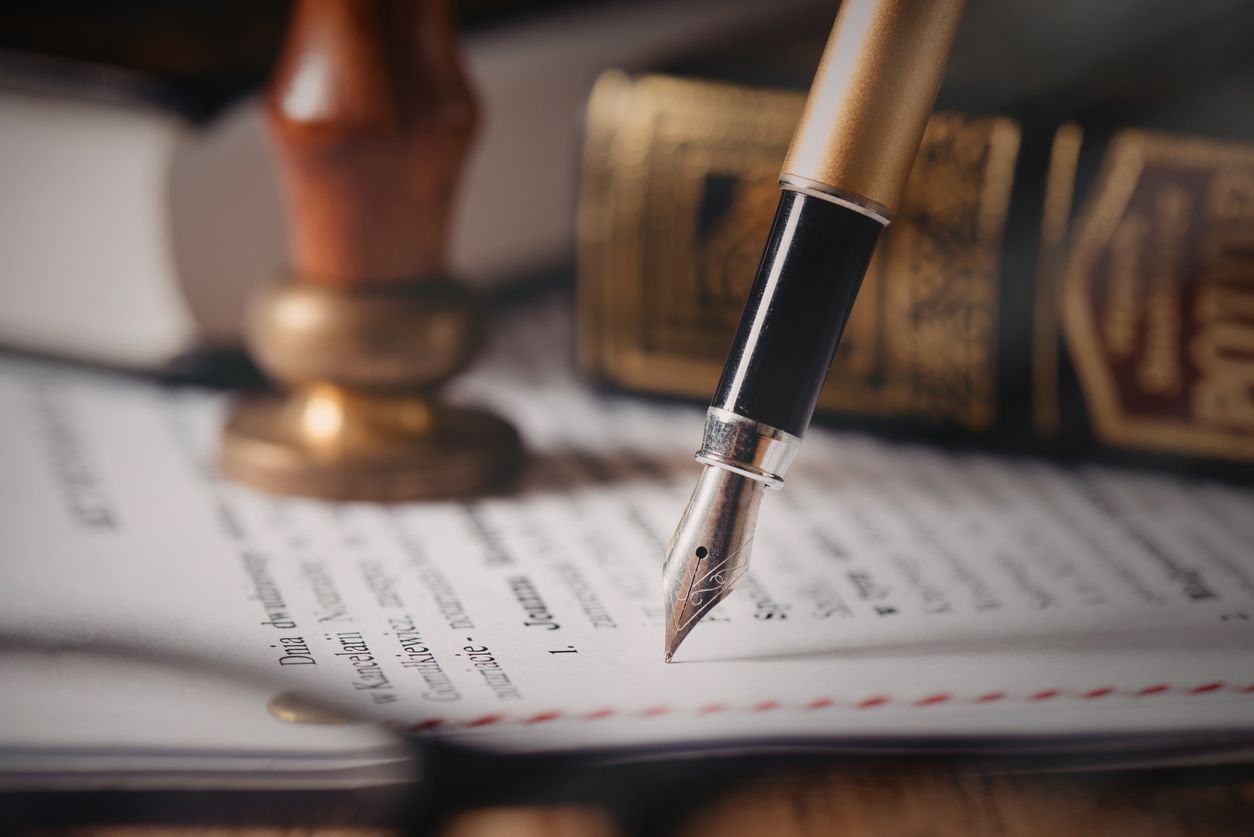 A fountain pen is sitting on top of a piece of paper next to a book.