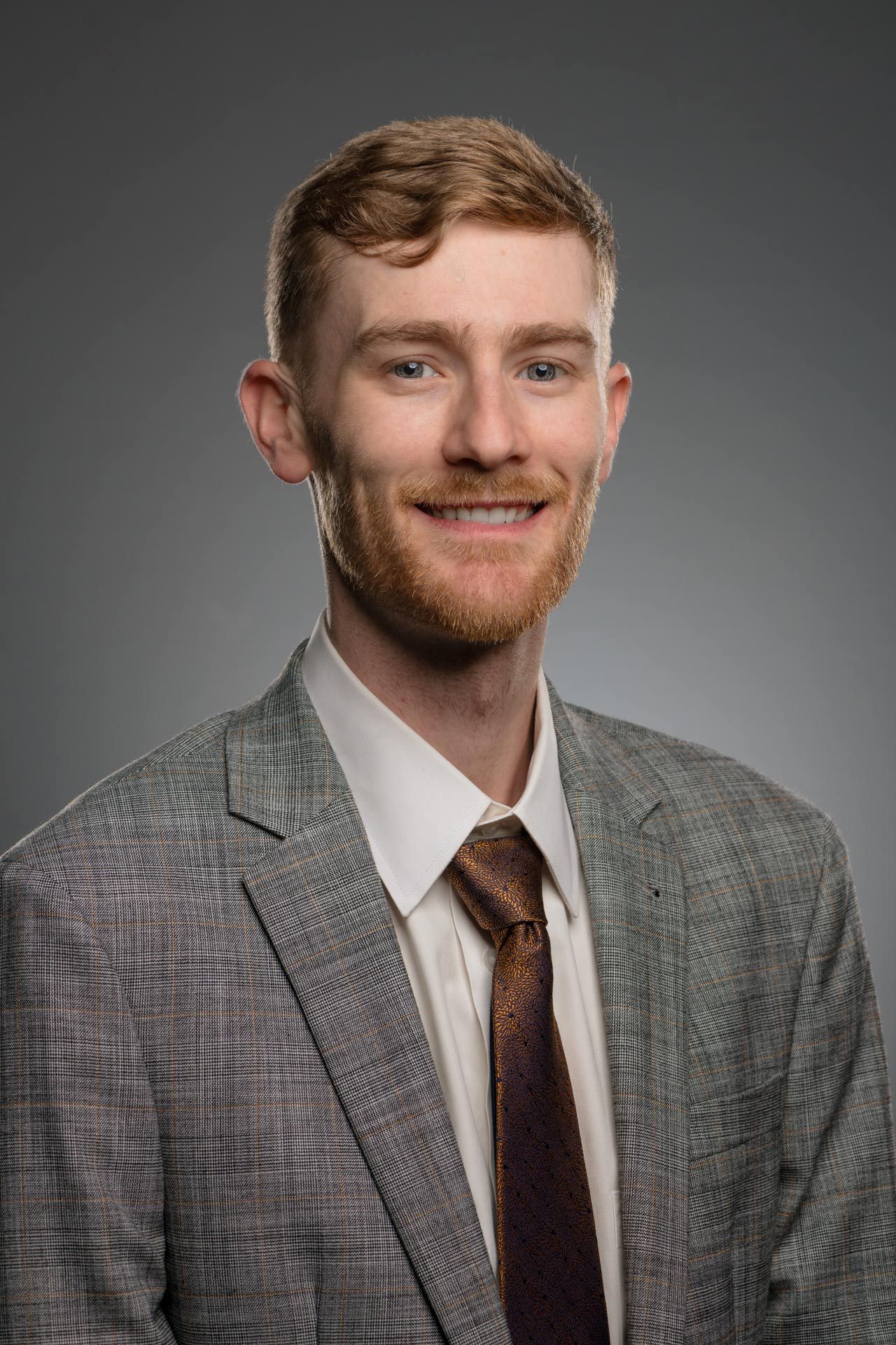 A man in a suit and tie is standing in front of a brick wall.