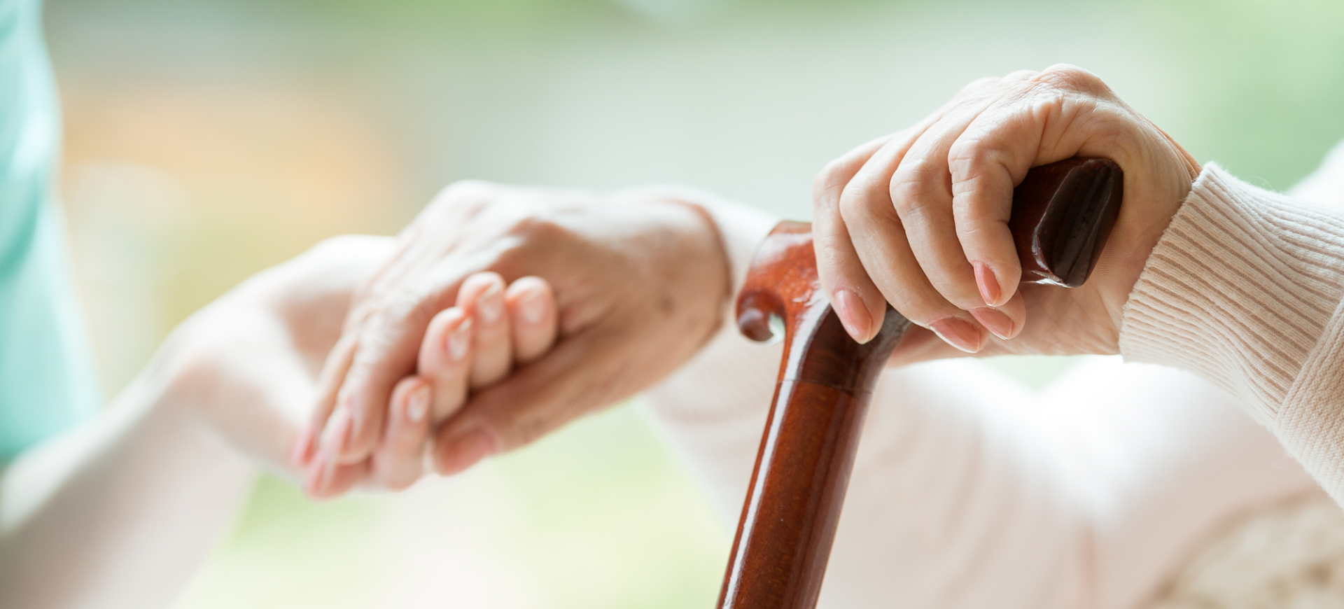 A person is helping an elderly woman with a cane.