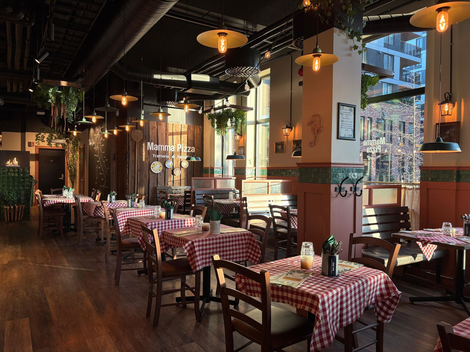 Interior of an Italian restaurant with red-checkered tablecloths, wooden chairs, and hanging lights.