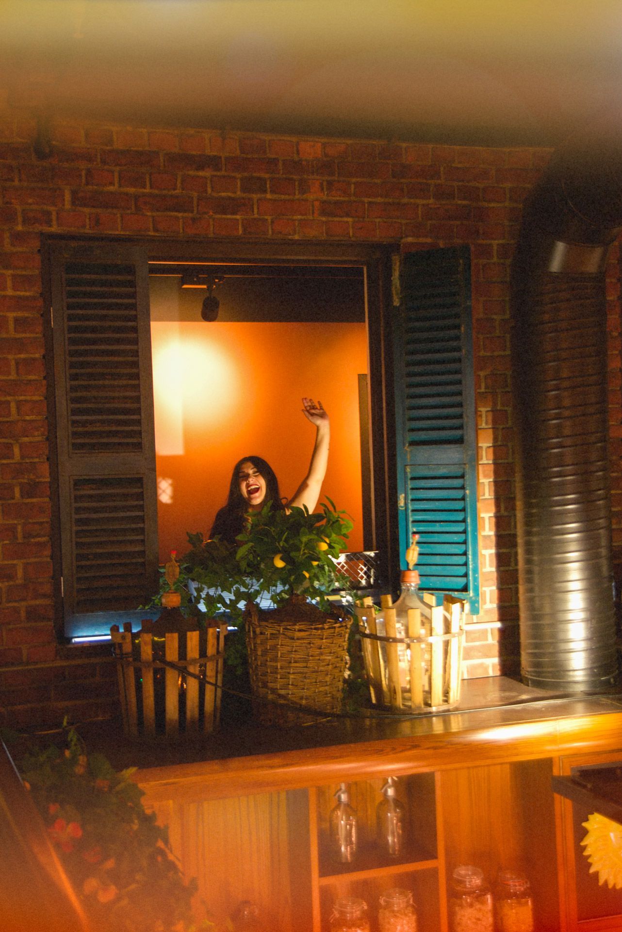Restaurant interior with red checkered tablecloths, patrons dining, and string lights.