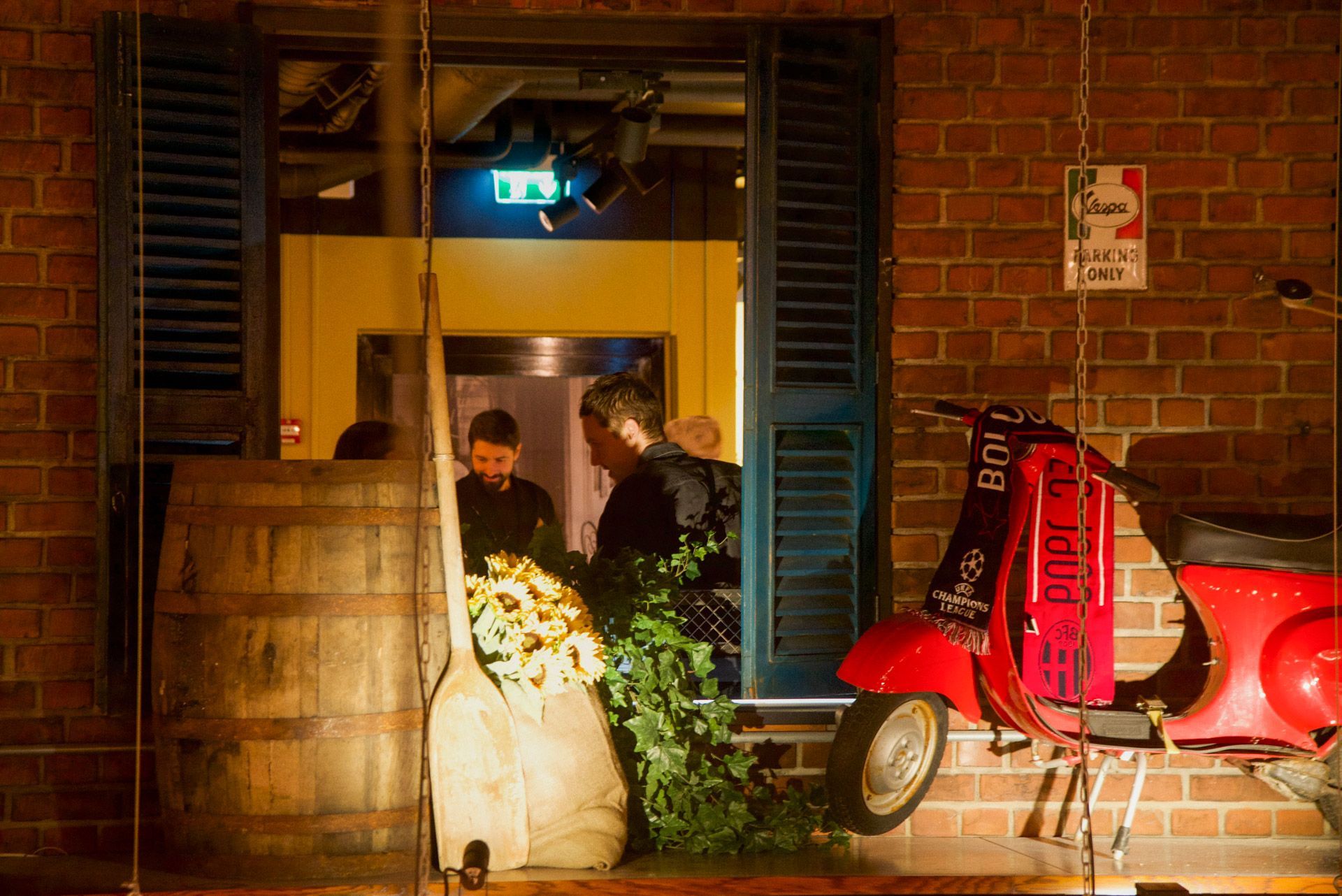Restaurant interior with bar, patrons, and staff behind the bar, olive green barstools.