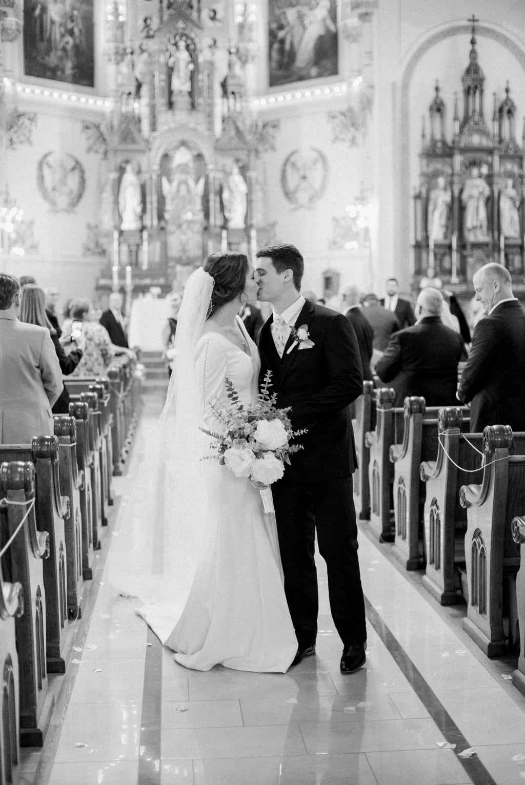 A bride and groom are kissing in a church.