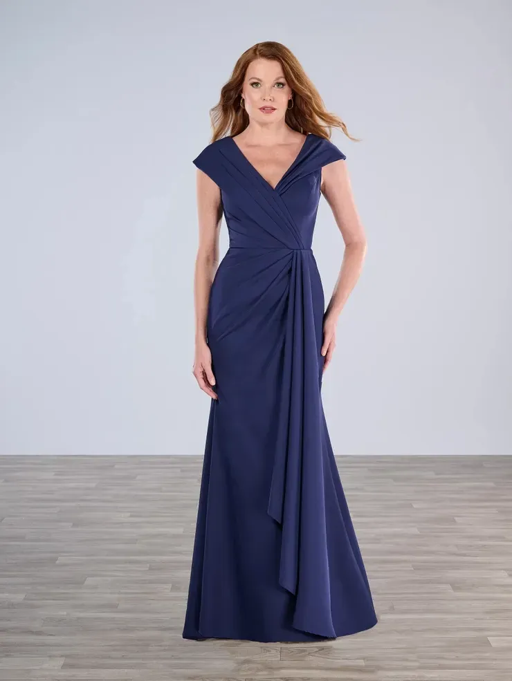 A woman in a long blue dress is standing on a wooden floor.