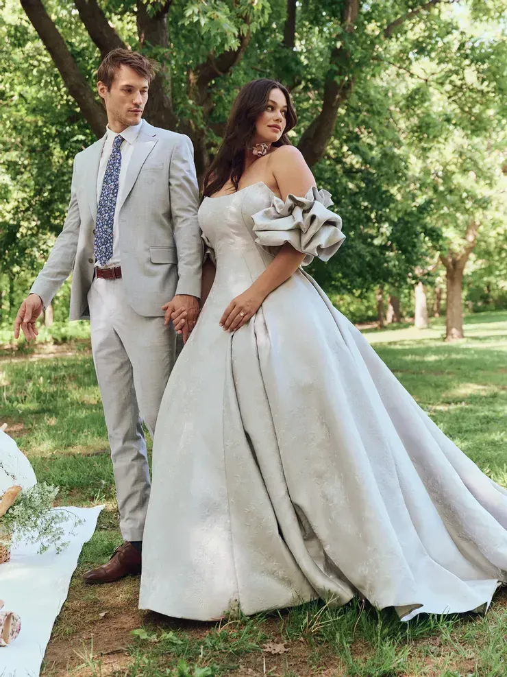 A bride and groom are posing for a picture in a park