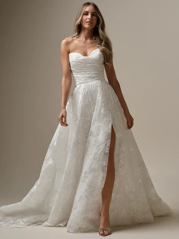 A woman is wearing a white wedding dress with a high slit.