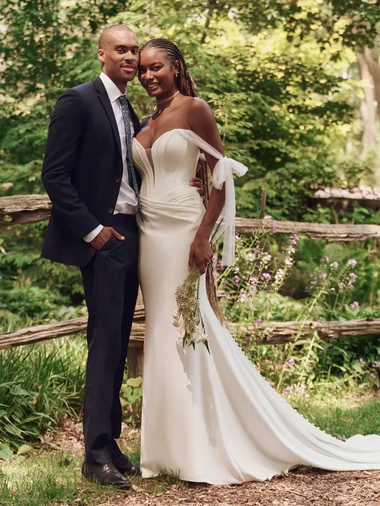 A man in a suit and a woman in a wedding dress are posing for a picture.