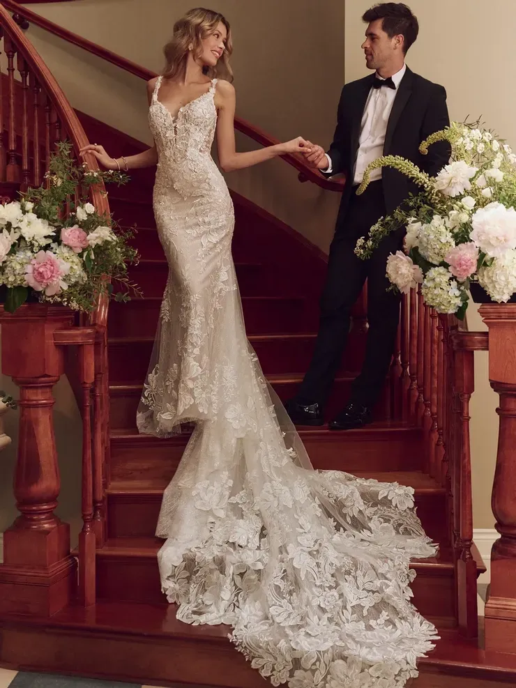 A bride and groom are standing on a set of stairs holding hands.