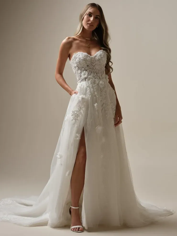 A woman is wearing a white wedding dress with a high slit.