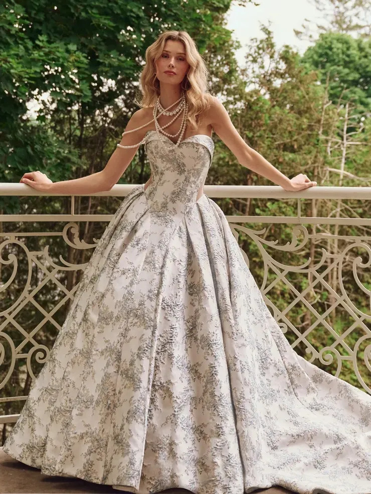 A woman in a ball gown is standing on a balcony.