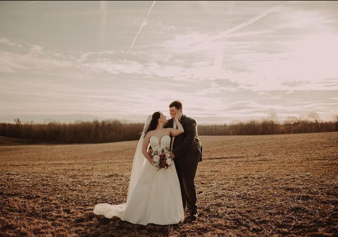 A bride and groom are kissing in a field.
