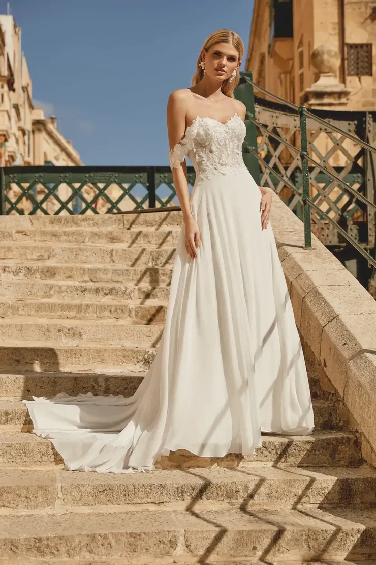 A woman in a white wedding dress is standing on a set of stairs.
