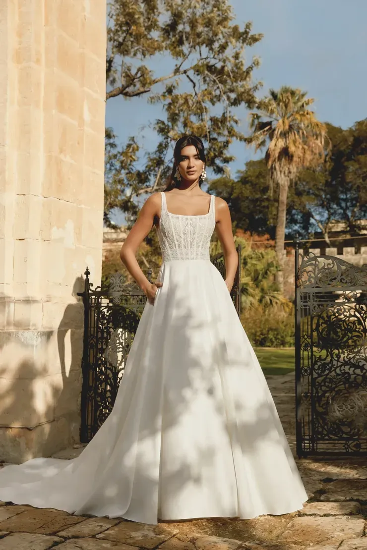 A woman in a white wedding dress is standing in front of a building.