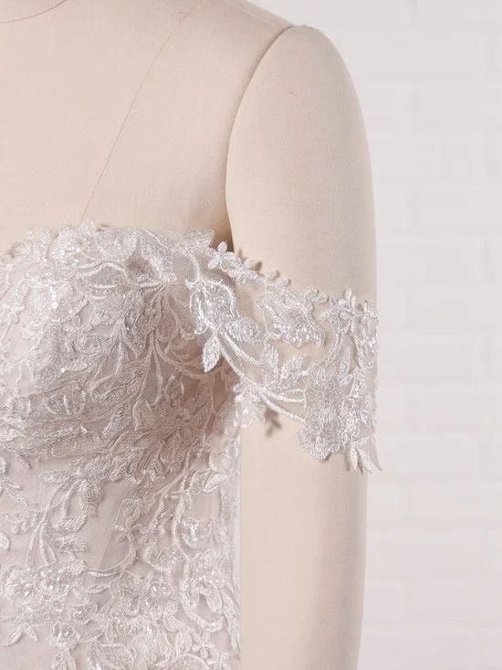 A close up of a white lace wedding dress on a mannequin.