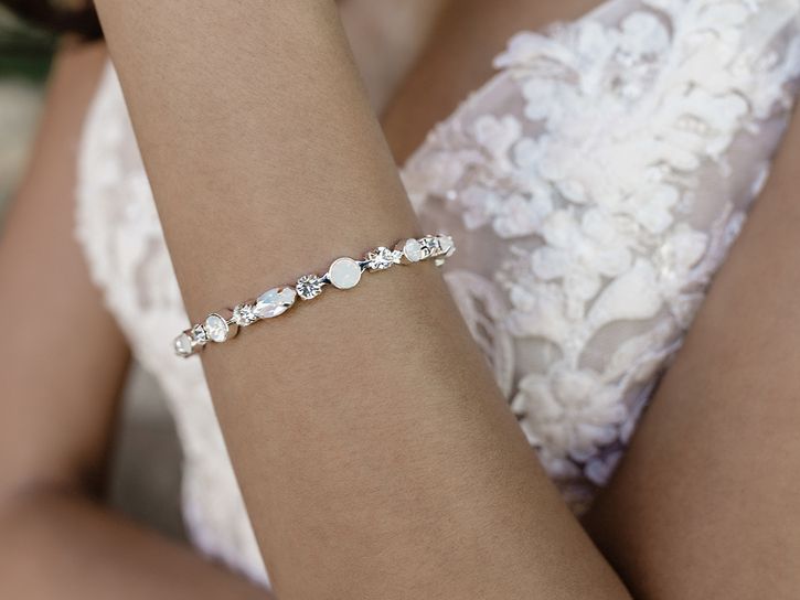 A woman in a white dress is wearing a bracelet on her wrist.