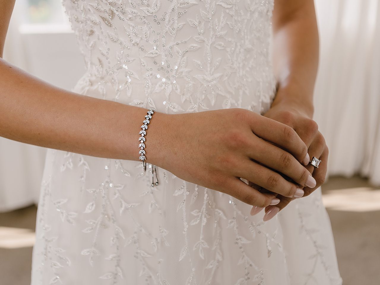 The bride is wearing a bracelet and a ring on her wrist.