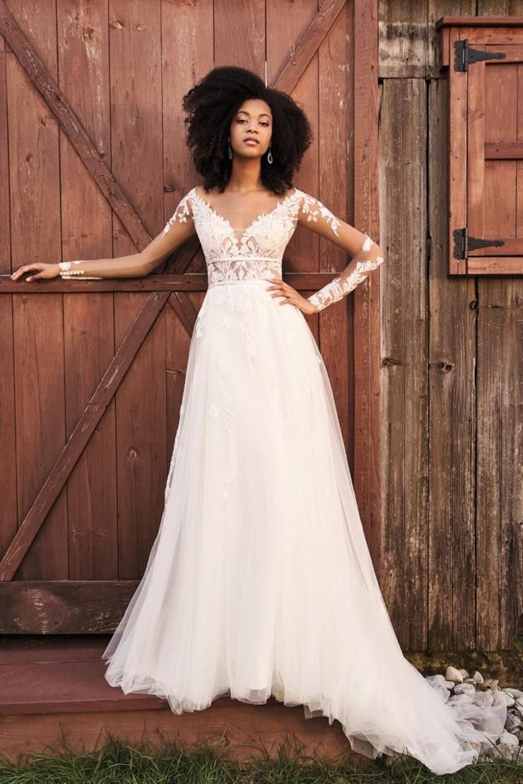 A woman in a wedding dress is standing in front of a wooden door.