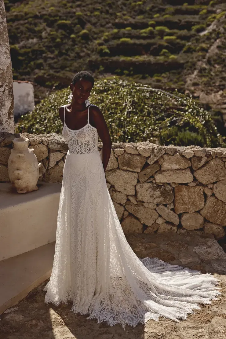 A woman in a wedding dress is standing in front of a stone wall.