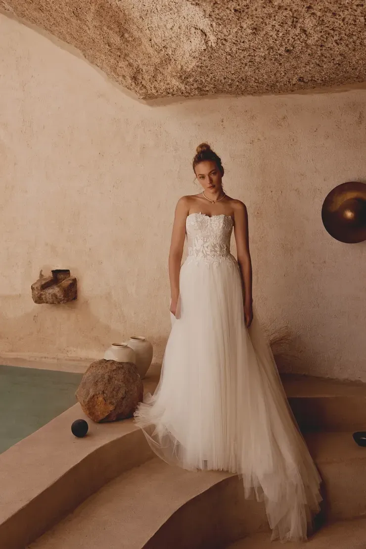A woman in a wedding dress is standing next to a pool.
