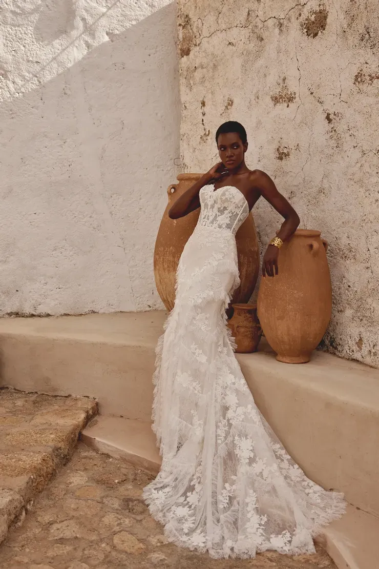 A woman in a wedding dress is standing next to a wall.