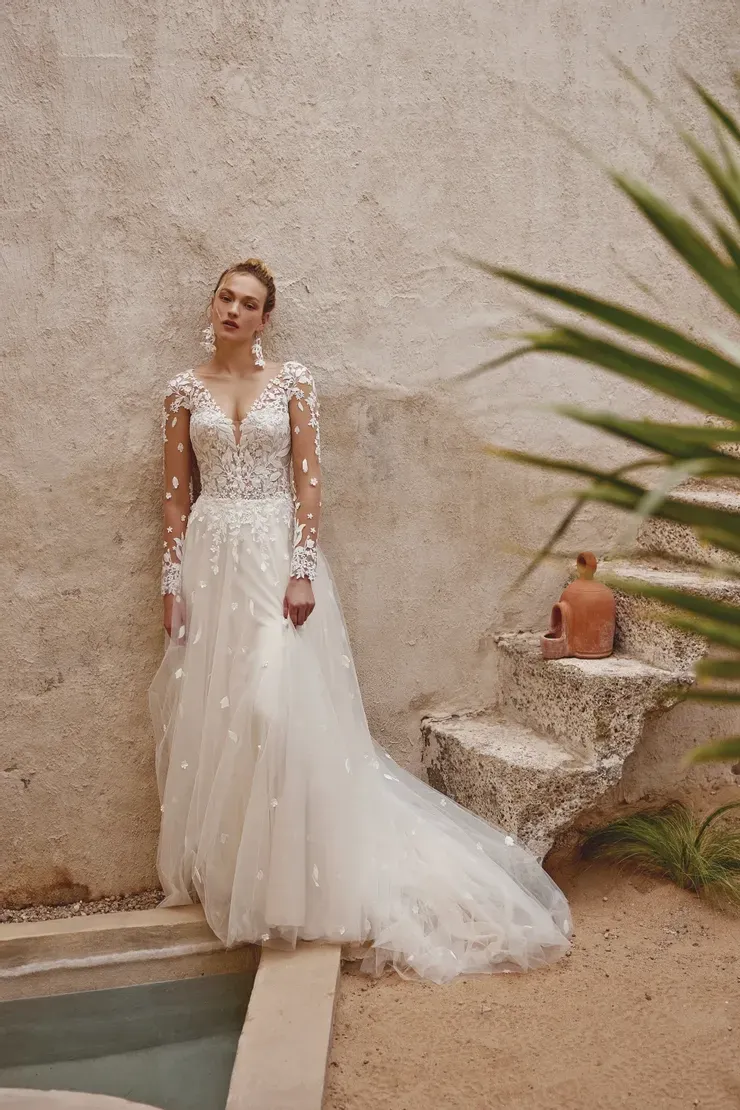 A woman in a wedding dress is standing next to a pool.