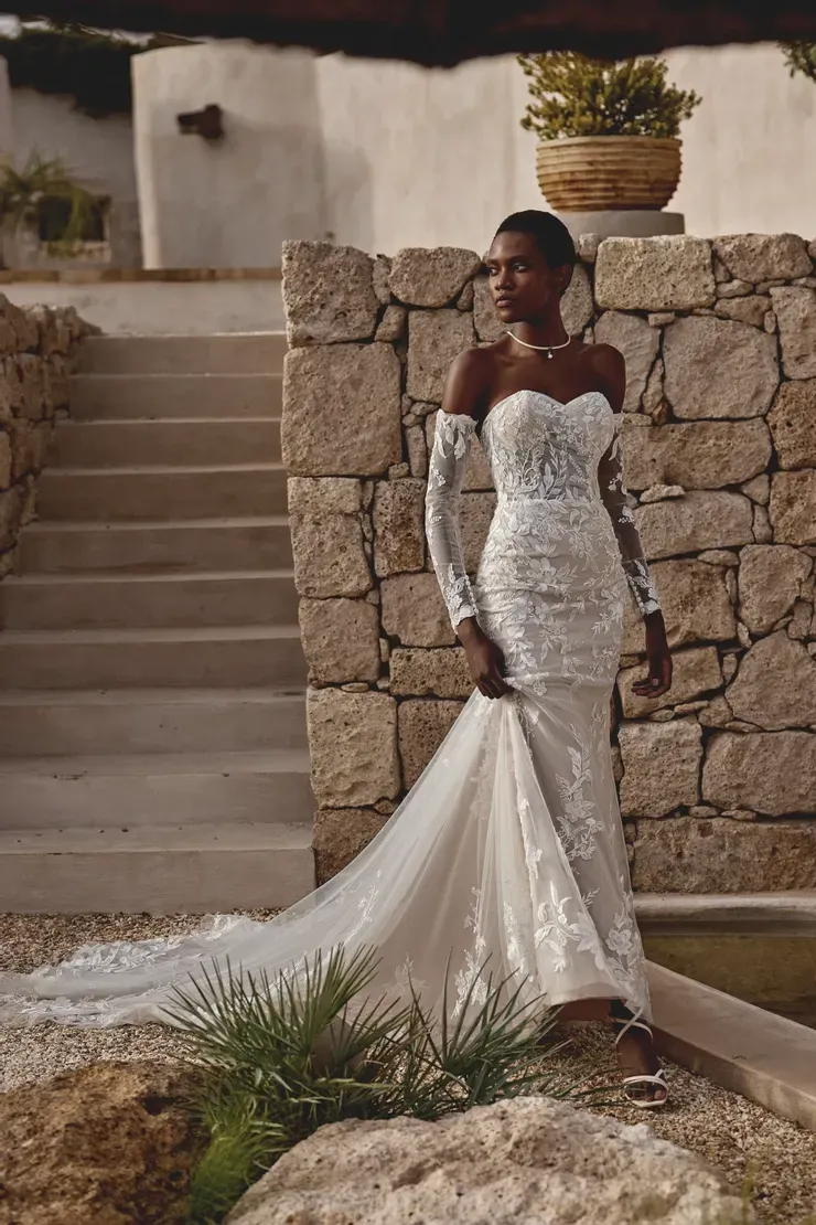 A woman in a wedding dress is standing next to a stone wall.