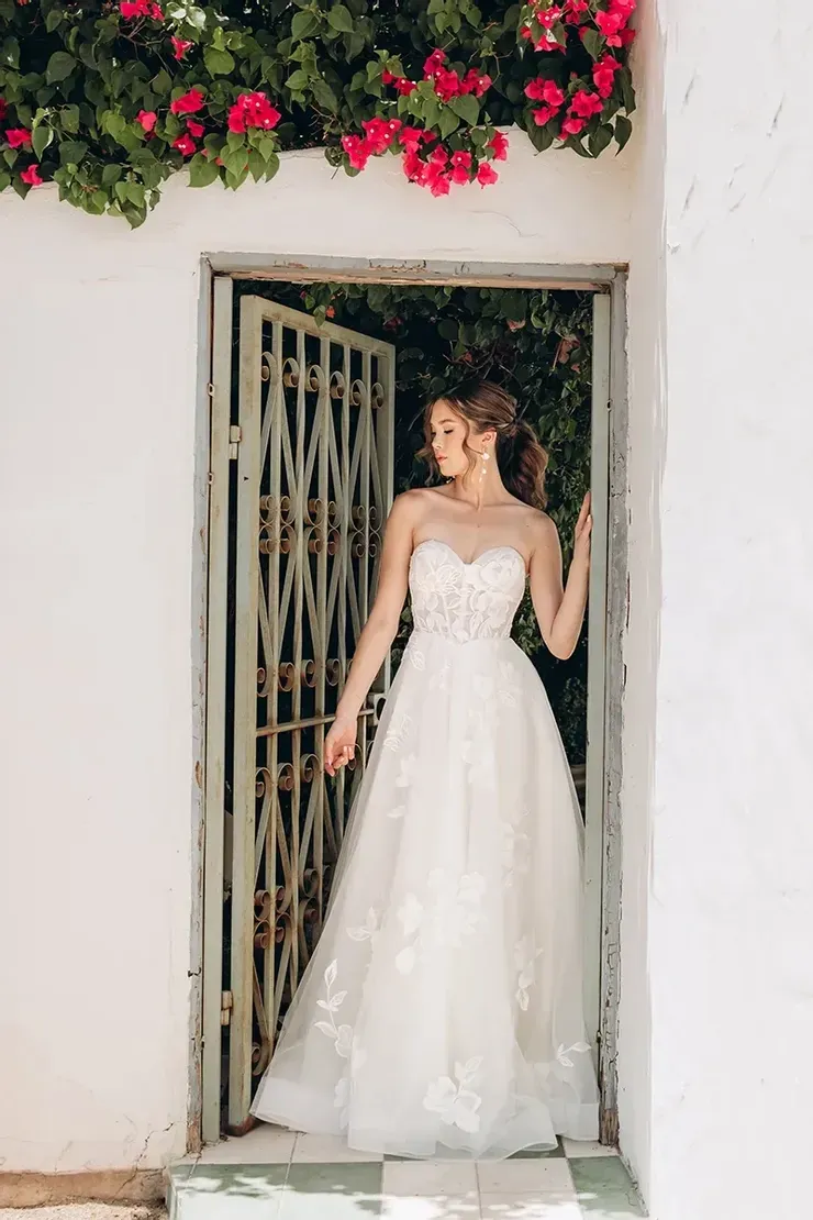 A woman in a wedding dress is standing in a doorway.