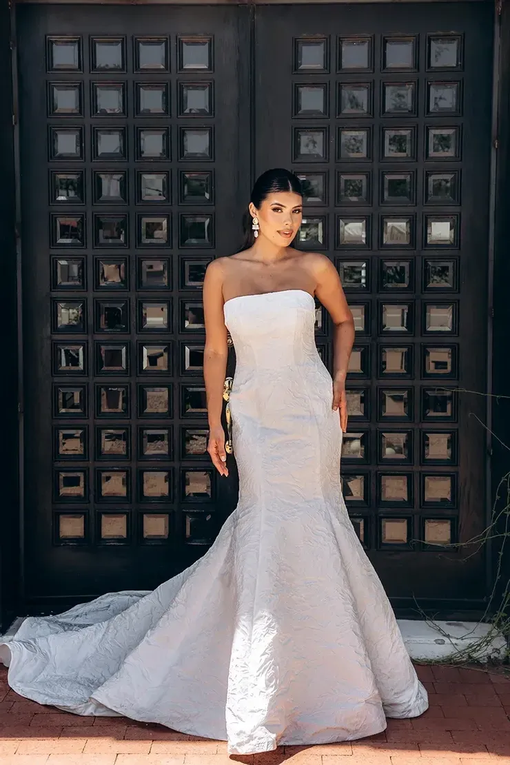 A woman in a wedding dress is standing in front of a door.