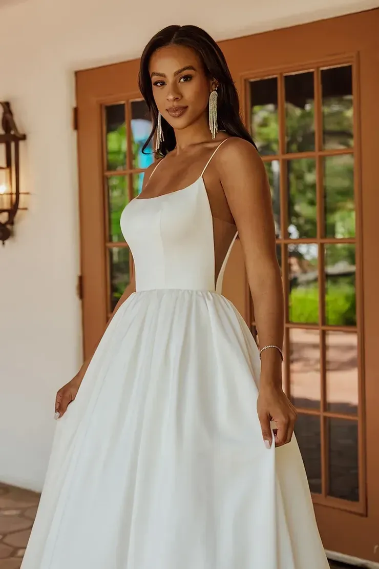 A woman in a white wedding dress is standing in front of a door.