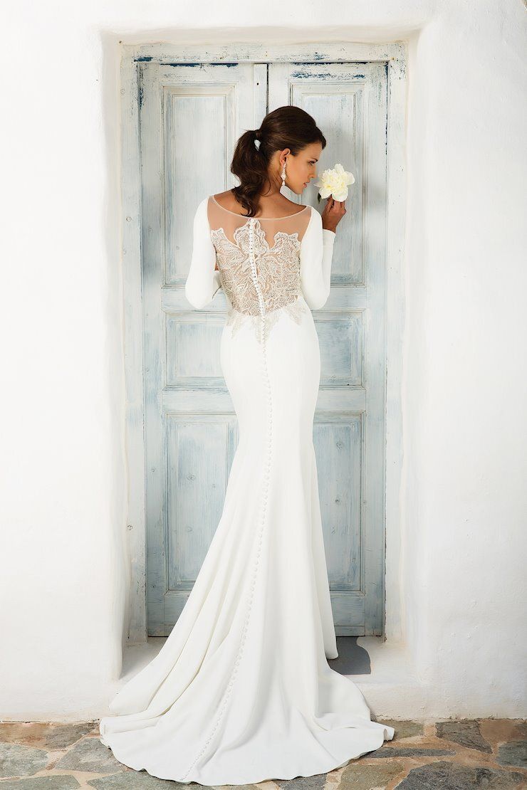 A woman in a wedding dress is standing in front of a door holding a bouquet of flowers.