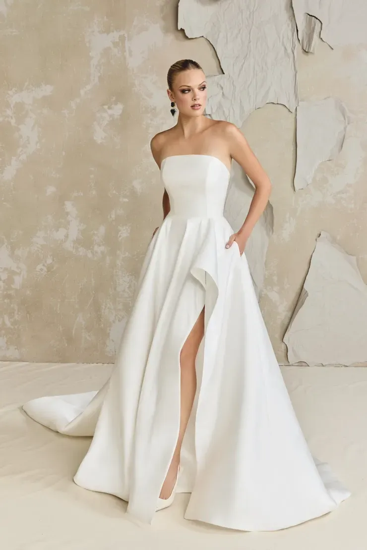 A woman is wearing a white strapless wedding dress with a high slit.