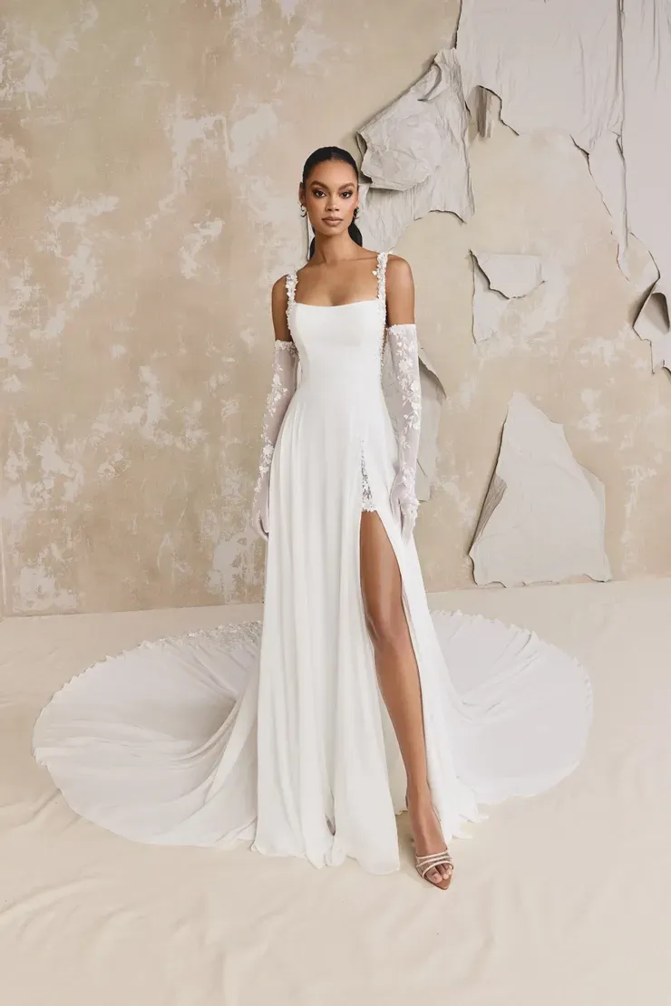 A woman is wearing a white wedding dress with a high slit and long gloves.