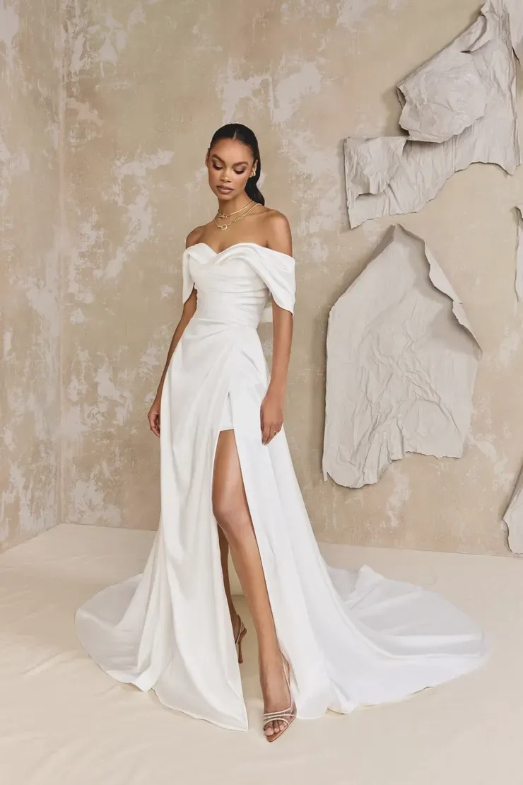 A woman is wearing a white wedding dress with a high slit.