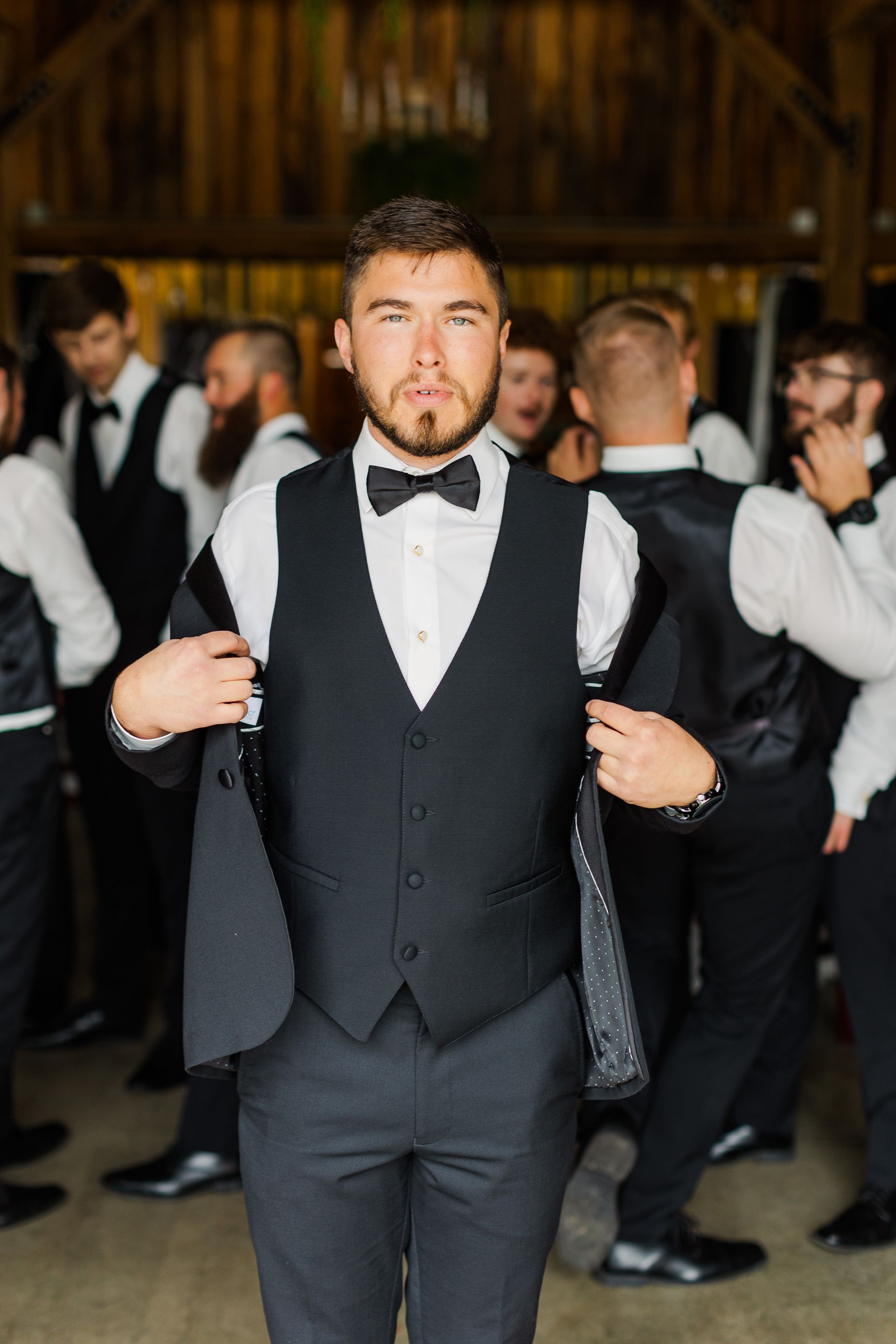 A man in a tuxedo and bow tie is standing in front of his groomsmen.