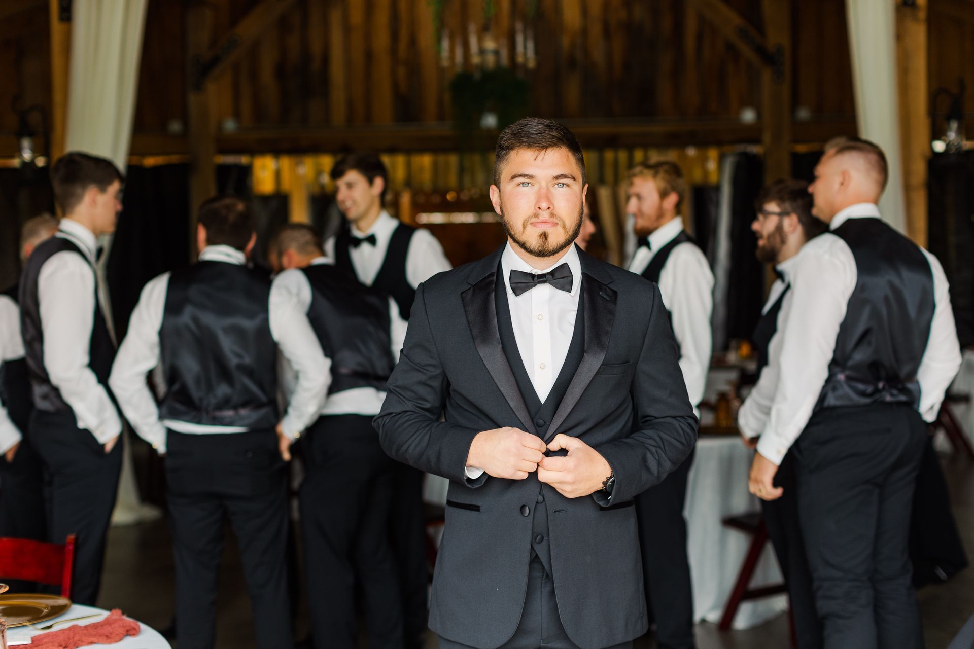 A man in a tuxedo is standing in front of his groomsmen.